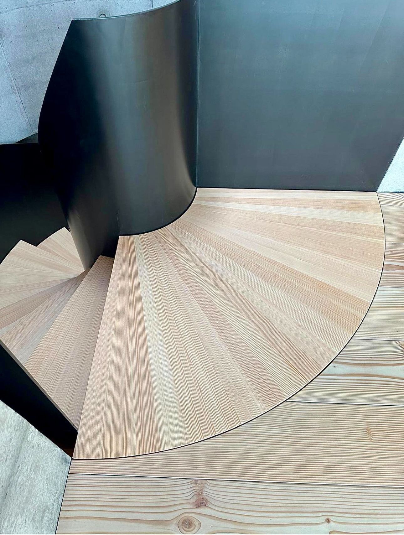 En spiraltrapp laget av tre og metall sitter på toppen av et tregulv.