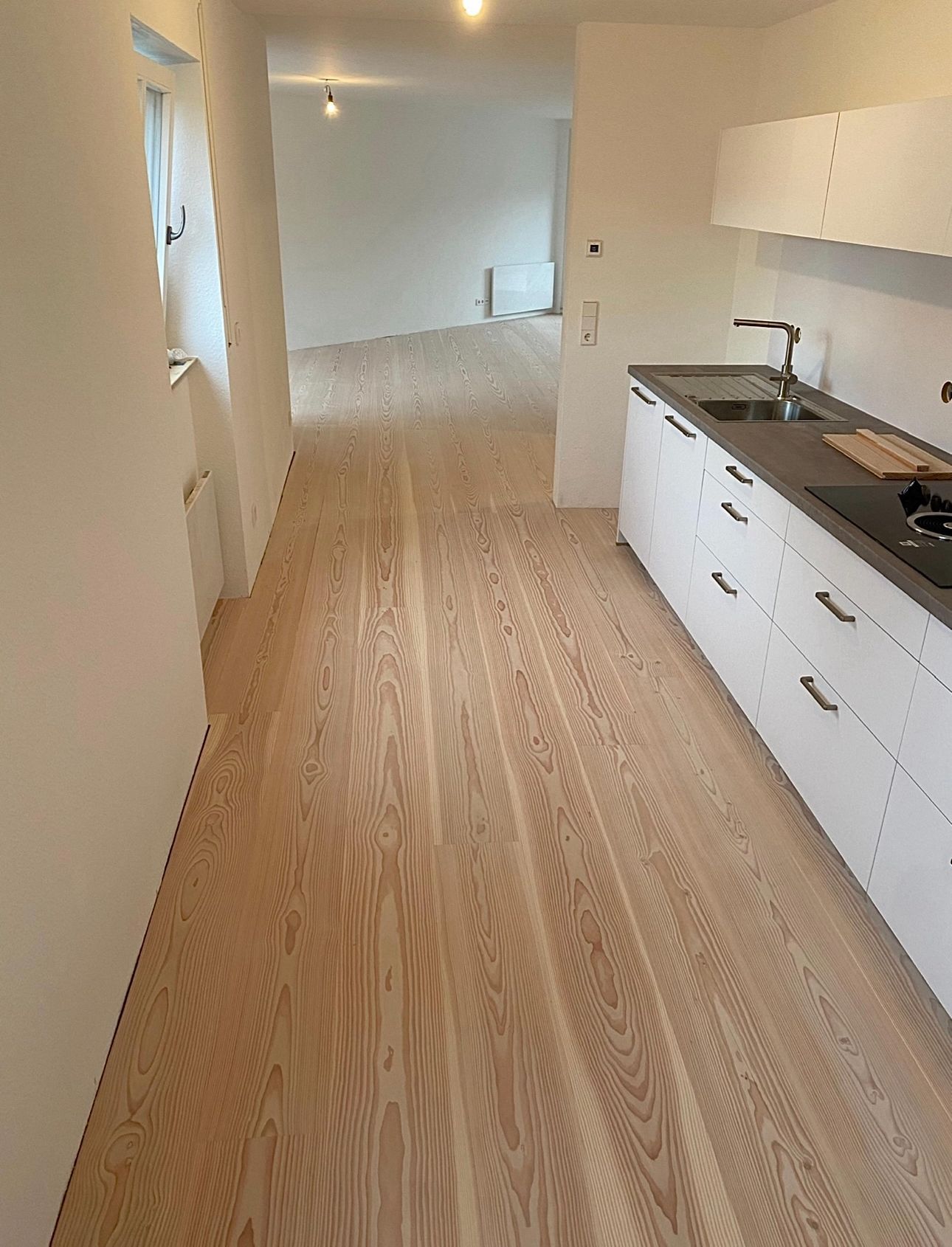 Et kjøkken med tregulv og hvite skap