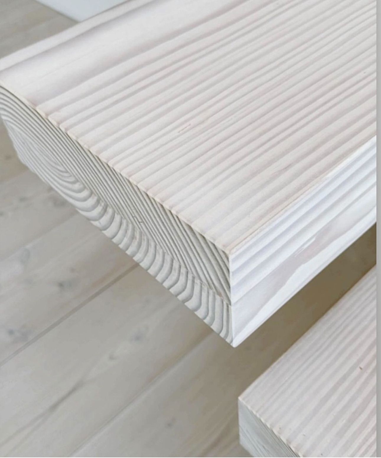 Et nærbilde av et stykke hvitt tre på et tregulv.