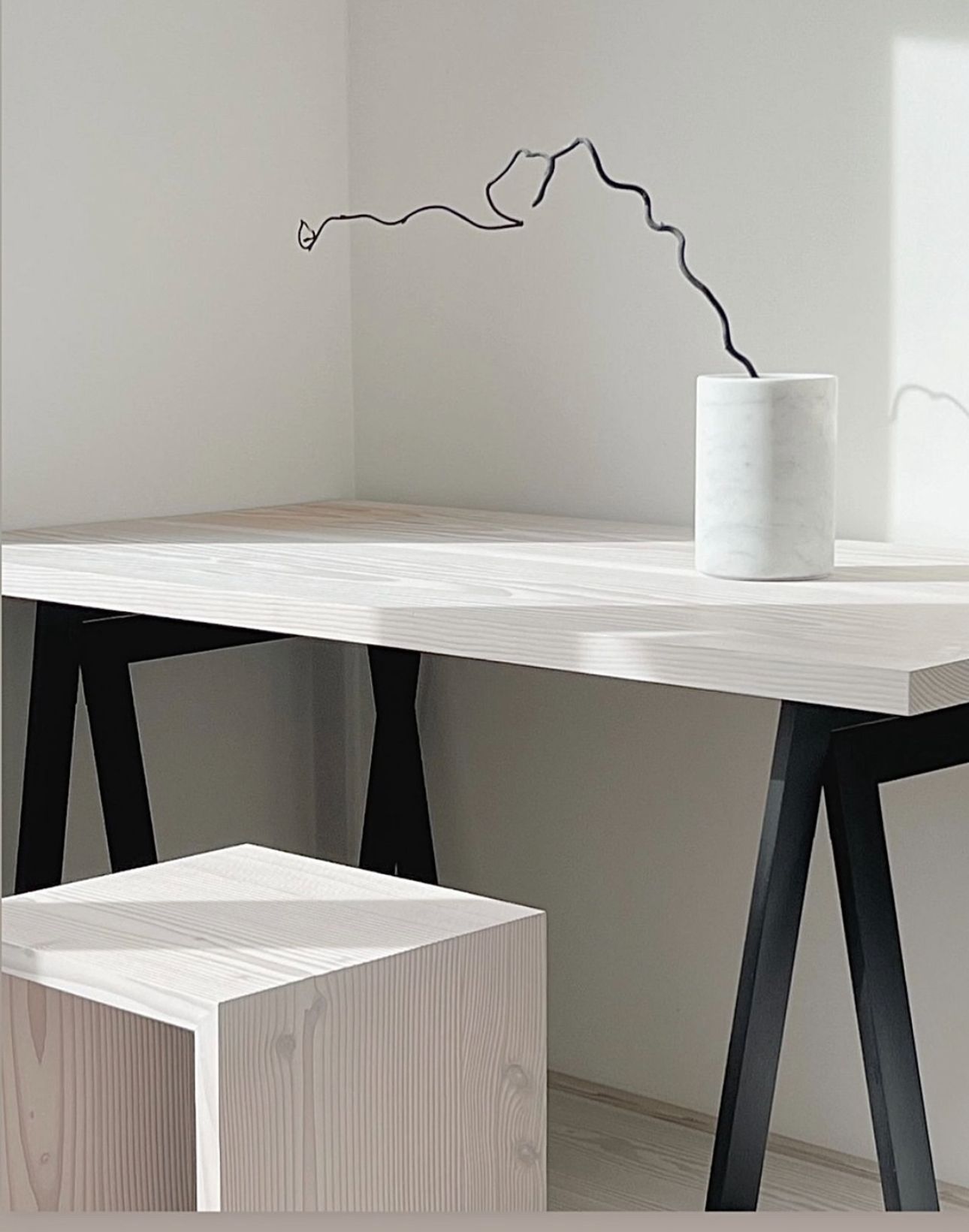 Et hvitt bord med en vase med blomster på