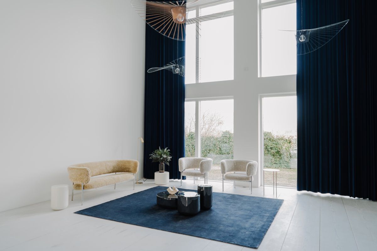 En stue med en sofa, stoler og et blått teppe.