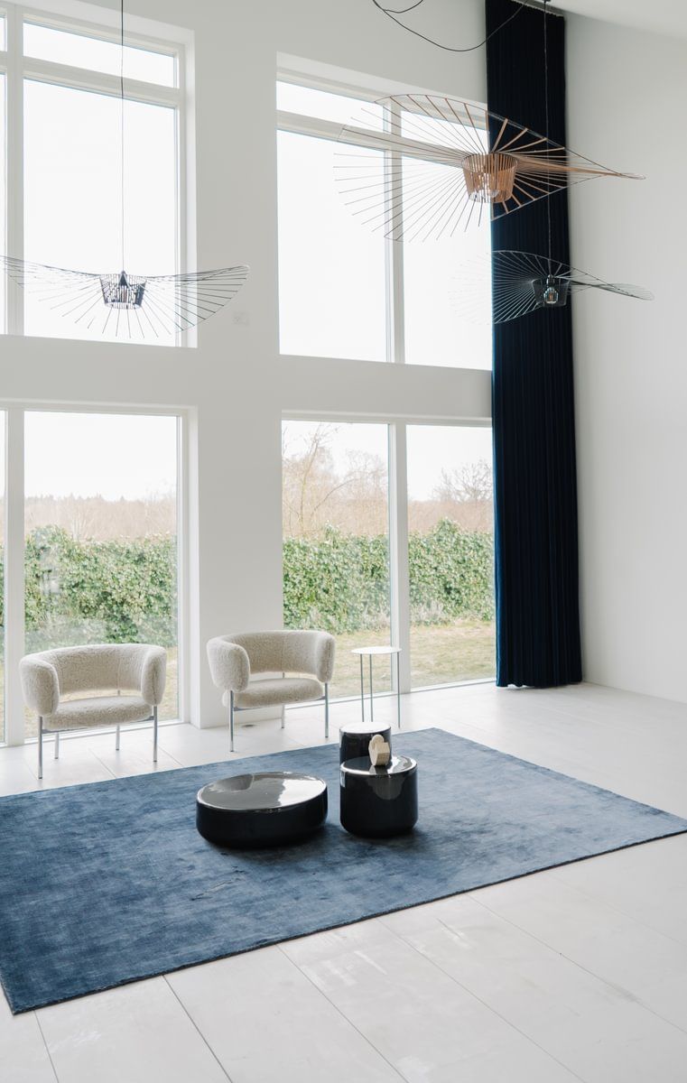 En stue med et blått teppe, to stoler, to bord og en takvifte.