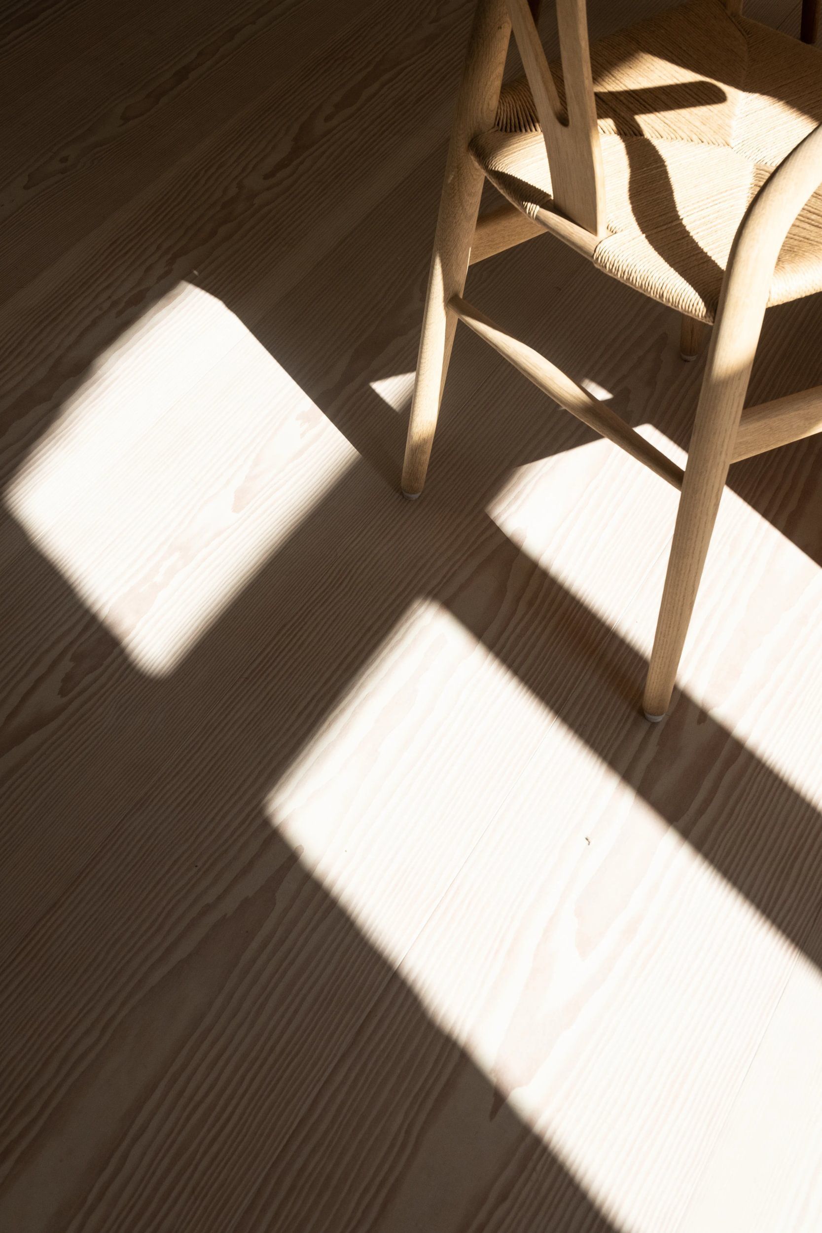 En trestol kaster en skygge på et tregulv.