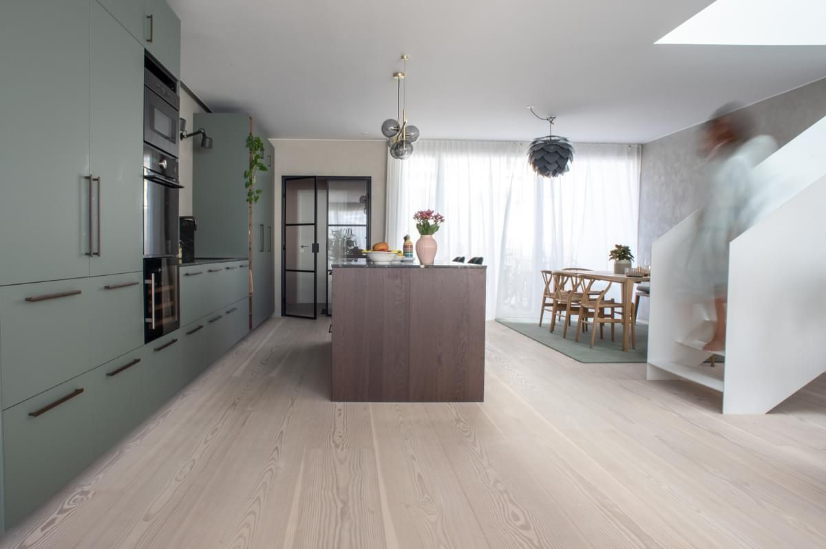 Et kjøkken med grønne skap og en stor øy midt i rommet.