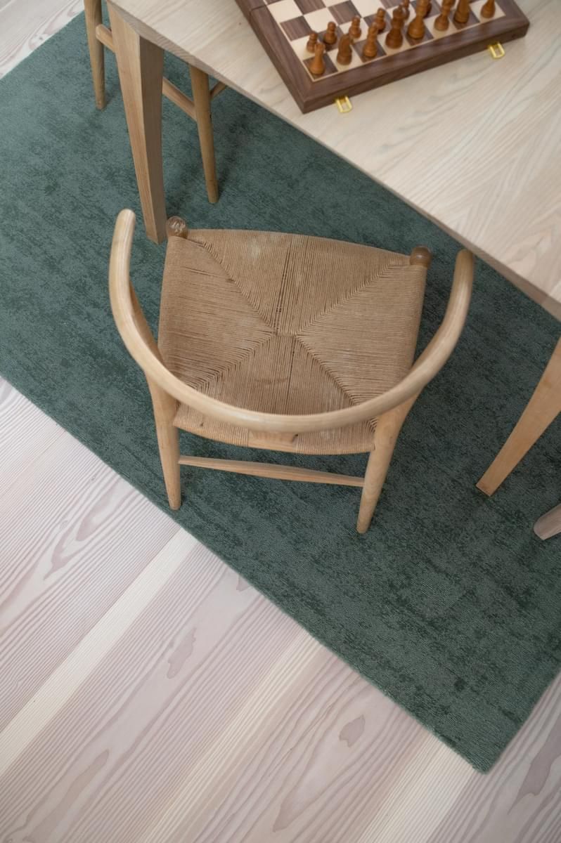 En stol sitter på et grønt teppe ved siden av et sjakkbrett.