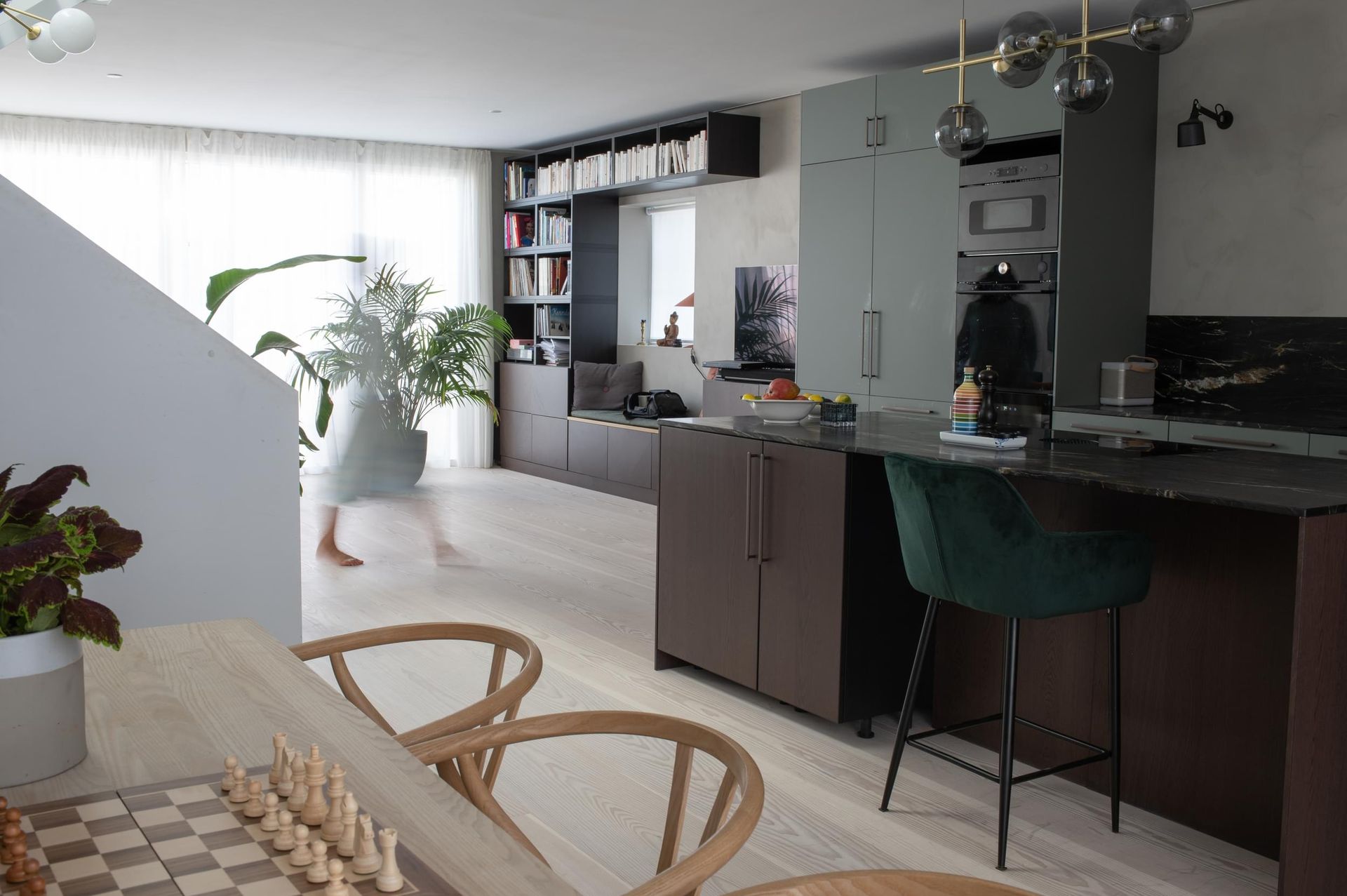 En kvinne går gjennom en stue med et sjakkbrett på bordet.