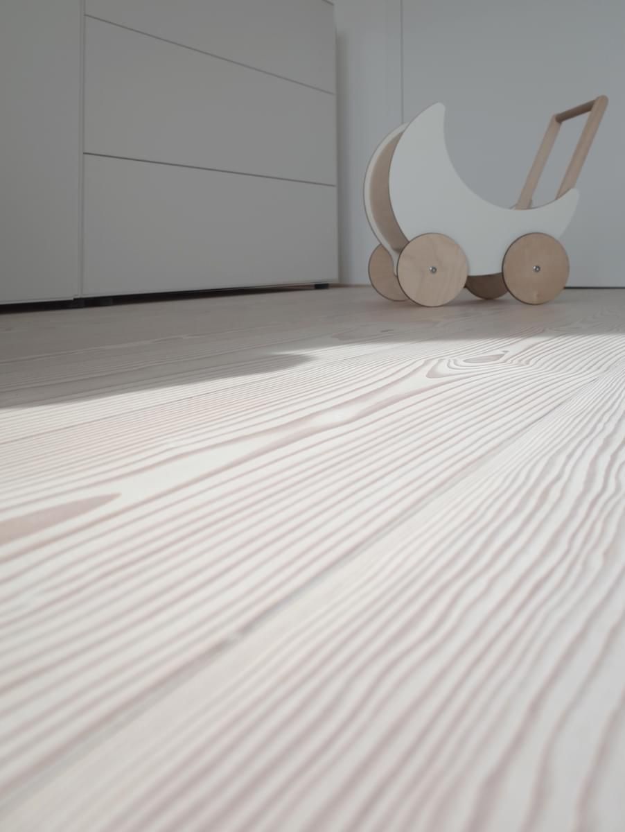 En trevogn sitter på et tregulv i et rom.