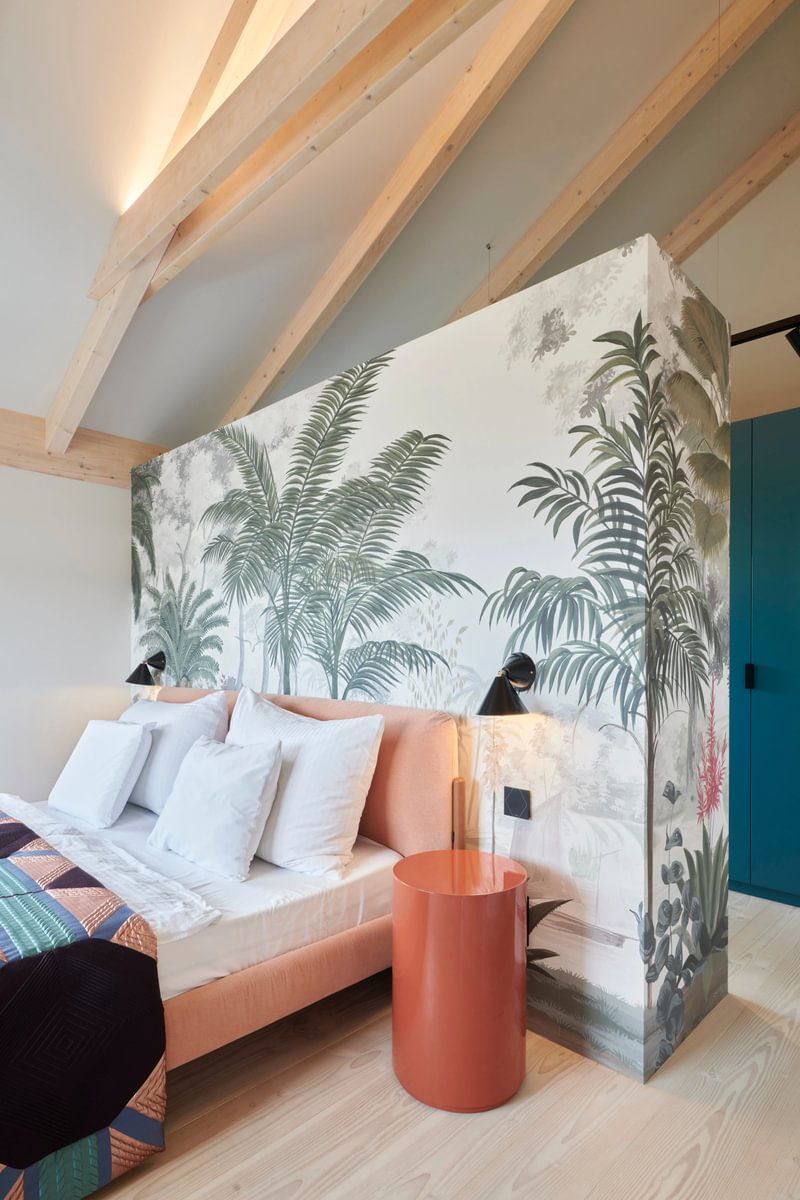 Et soverom med seng, nattbord og et veggmaleri på veggen.