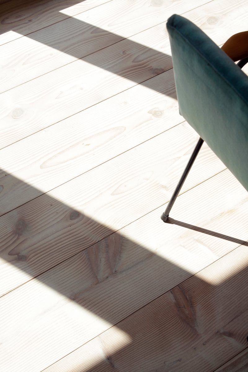 En stol sitter på et tregulv med en skygge på.