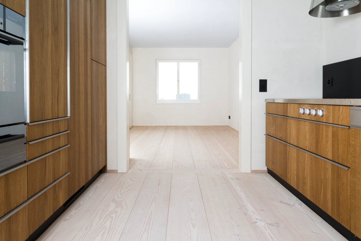 Et kjøkken med treskap og hvitevarer i rustfritt stål