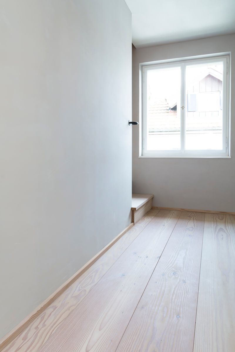Et tomt rom med tregulv og vindu.