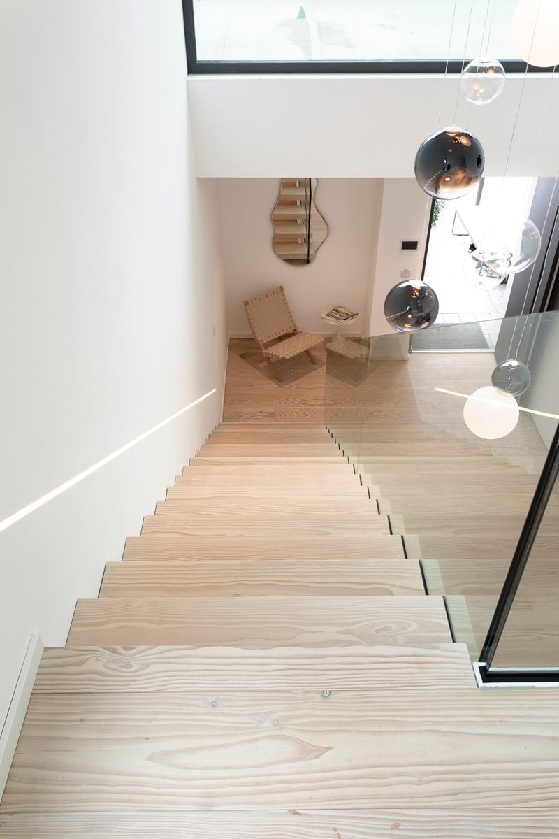 En tretrapp med glassrekkverk som fører opp til andre etasje i et hus.