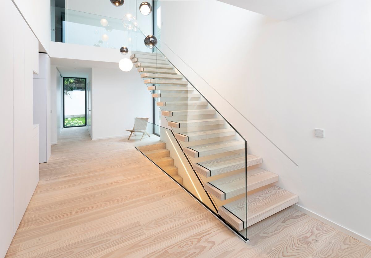 En moderne trapp med glassrekkverk i en gang.