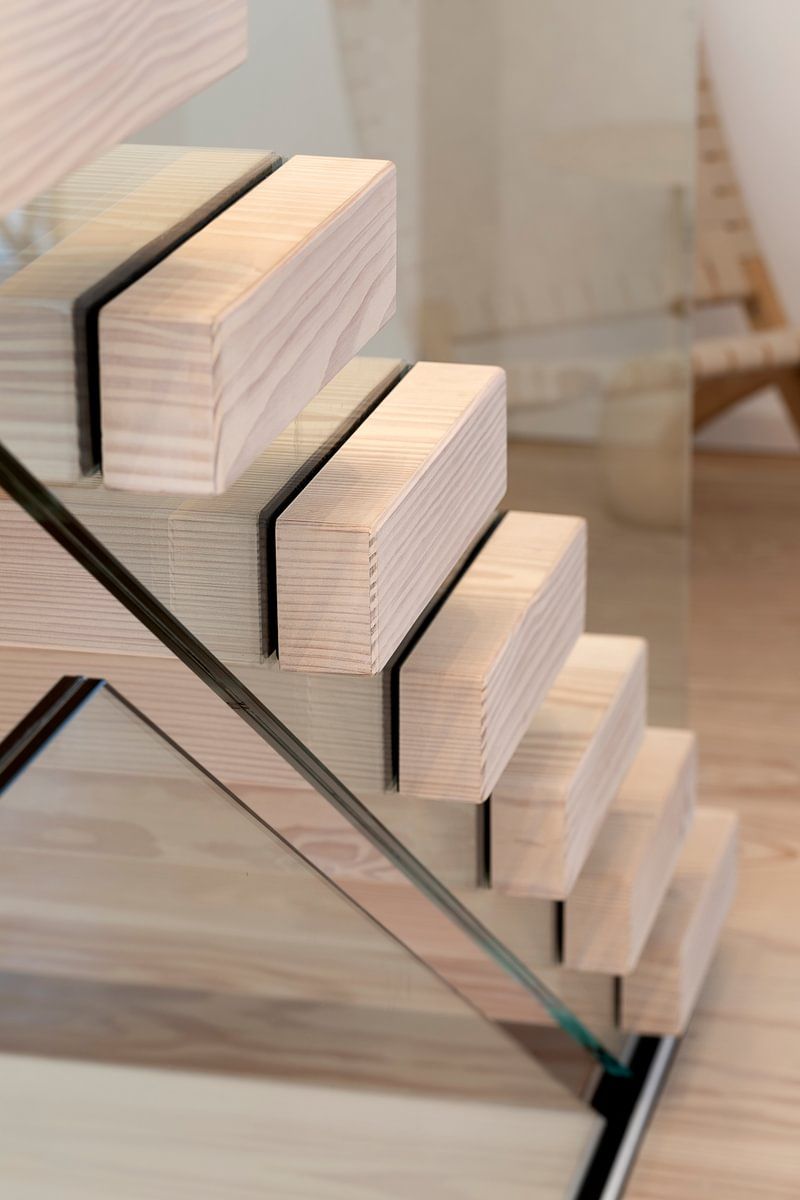 Et nærbilde av en tretrapp med et glassrekkverk