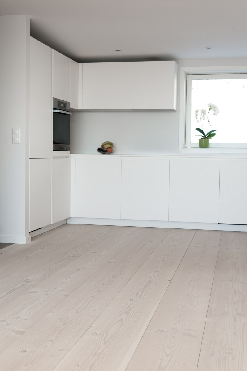 Et kjøkken med hvite skap og tregulv
