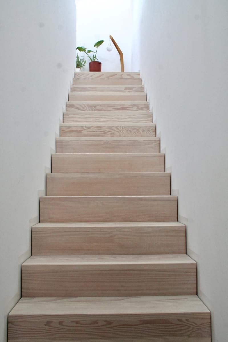 Et sett med tretrapper som fører opp til en hvit vegg.