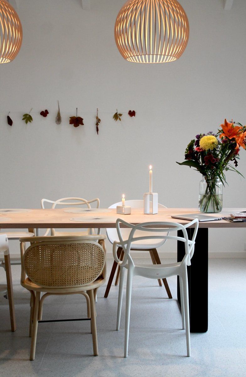 Et spisebord med stoler og en vase med blomster på