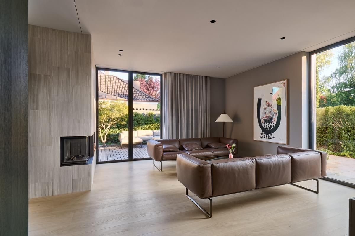 En stue med sofa , peis og store vinduer.