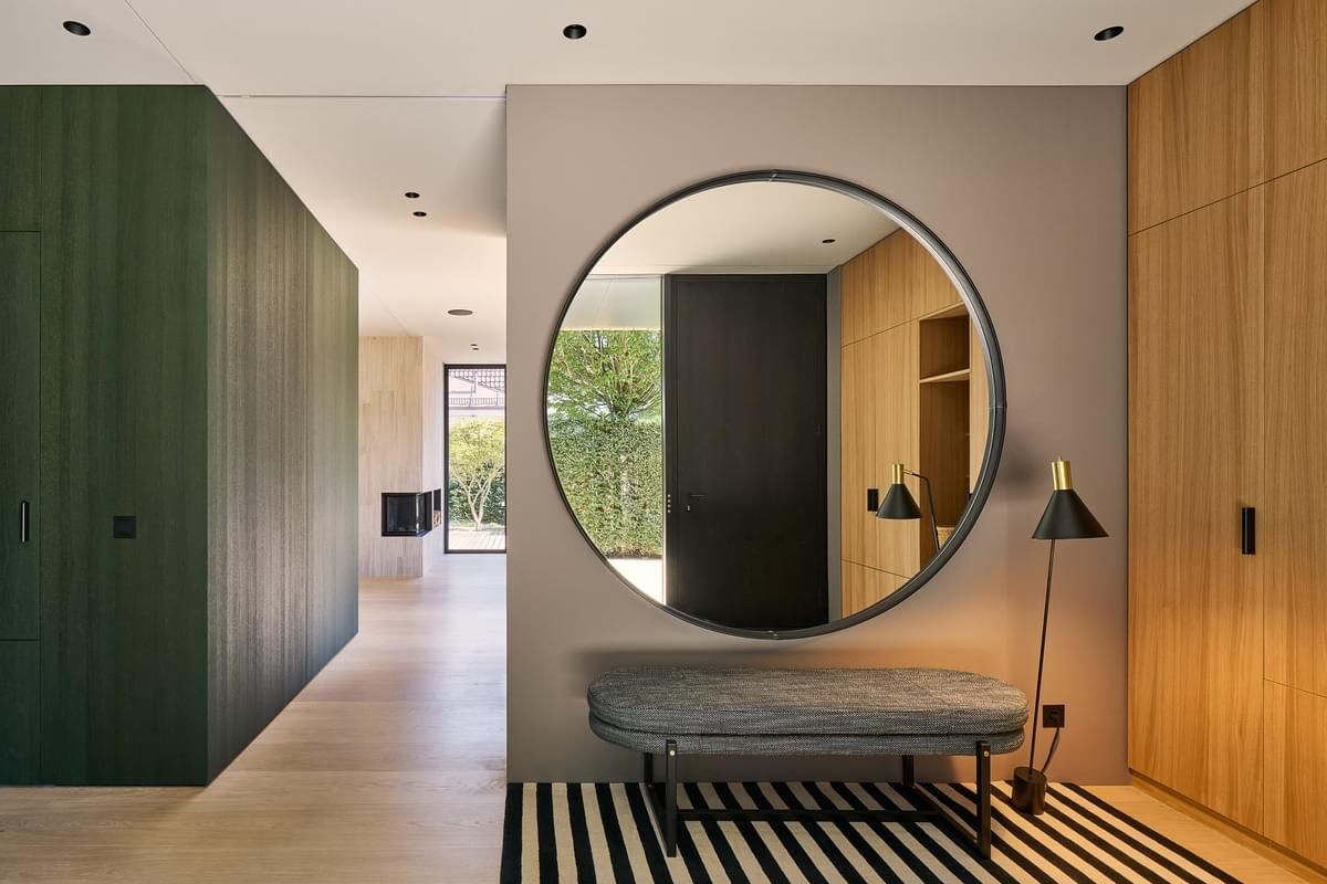 En gang med et rundt speil på veggen og en benk.