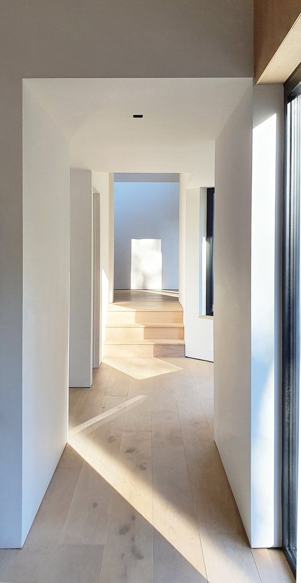 En gang i et hus med tregulv og hvite vegger.