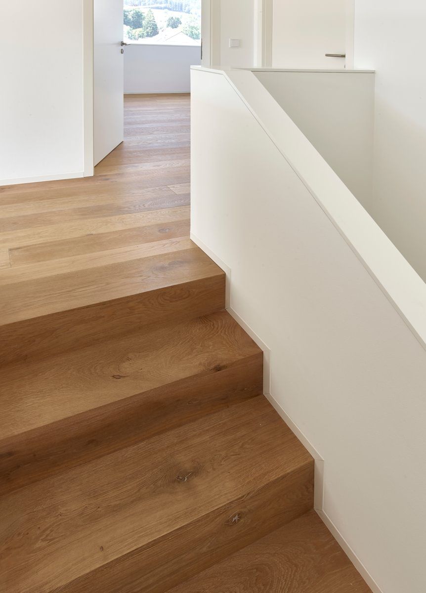 En trapp med tretrapper og et hvitt rekkverk i et hus.