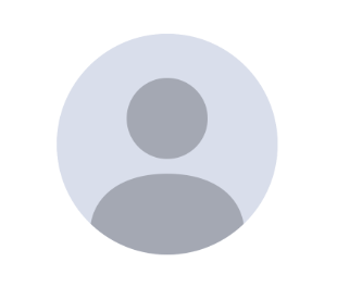 A woman is sitting at a desk wearing glasses and a purple shirt.