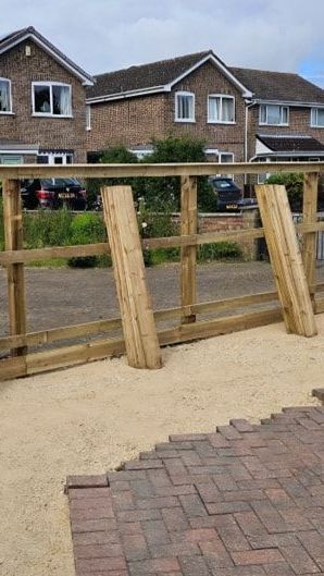 A wooden fence is being built in front of a brick house.