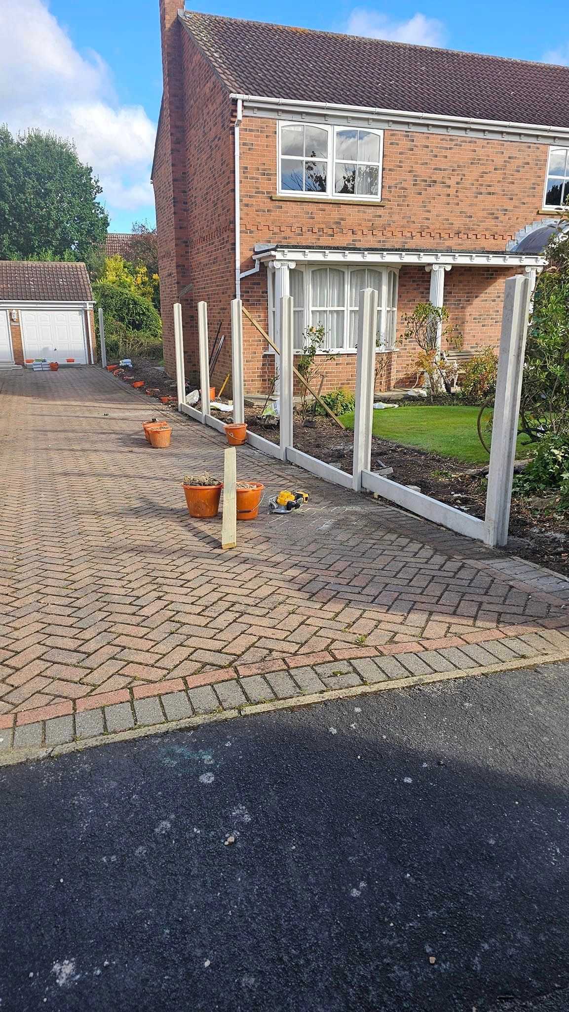 A brick house with a driveway and a fence in front of it.