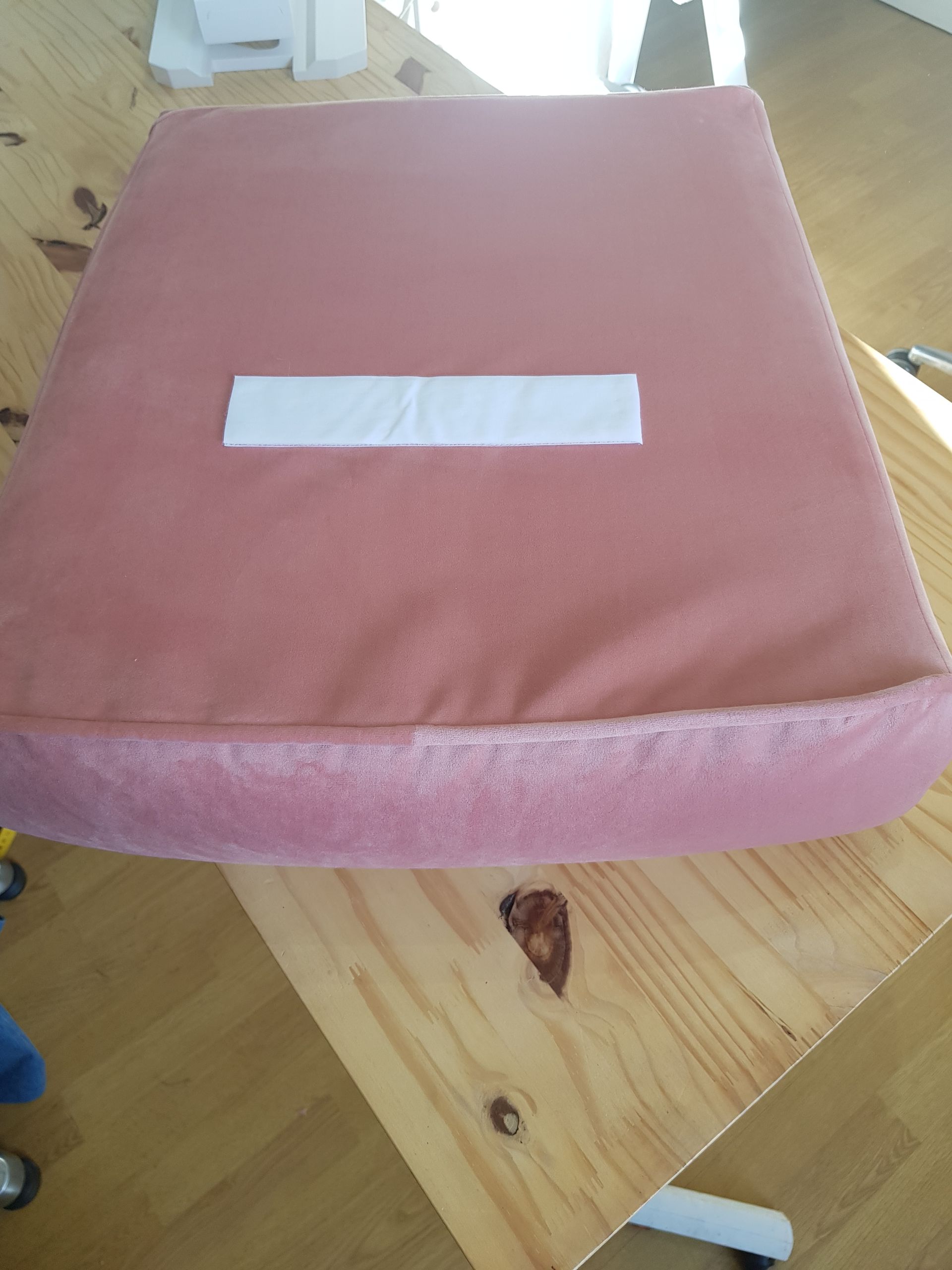 Un coussin rose est posé sur une table en bois.