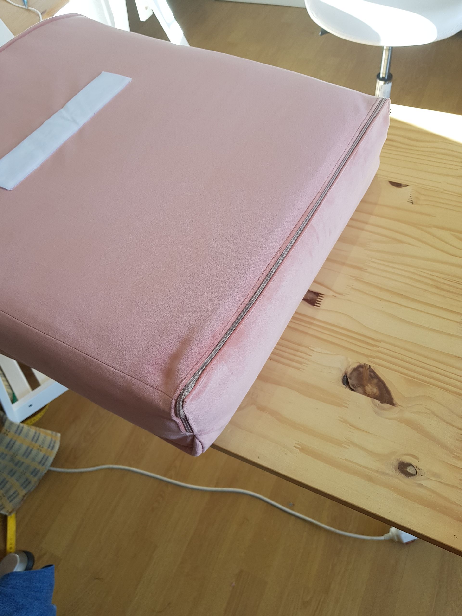 Un coussin rose est posé sur une table en bois