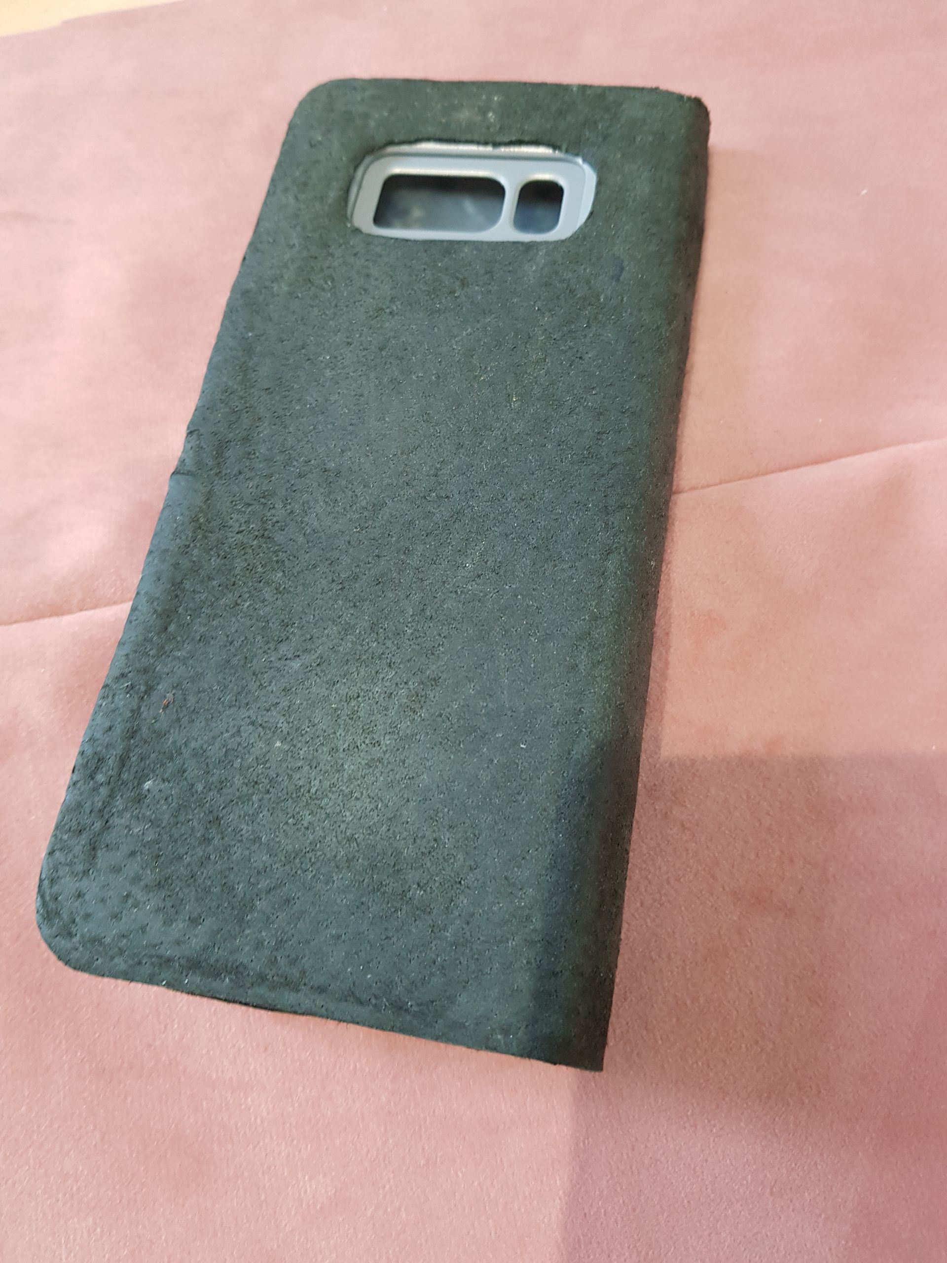 Une coque de téléphone noire est posée sur un tissu rose