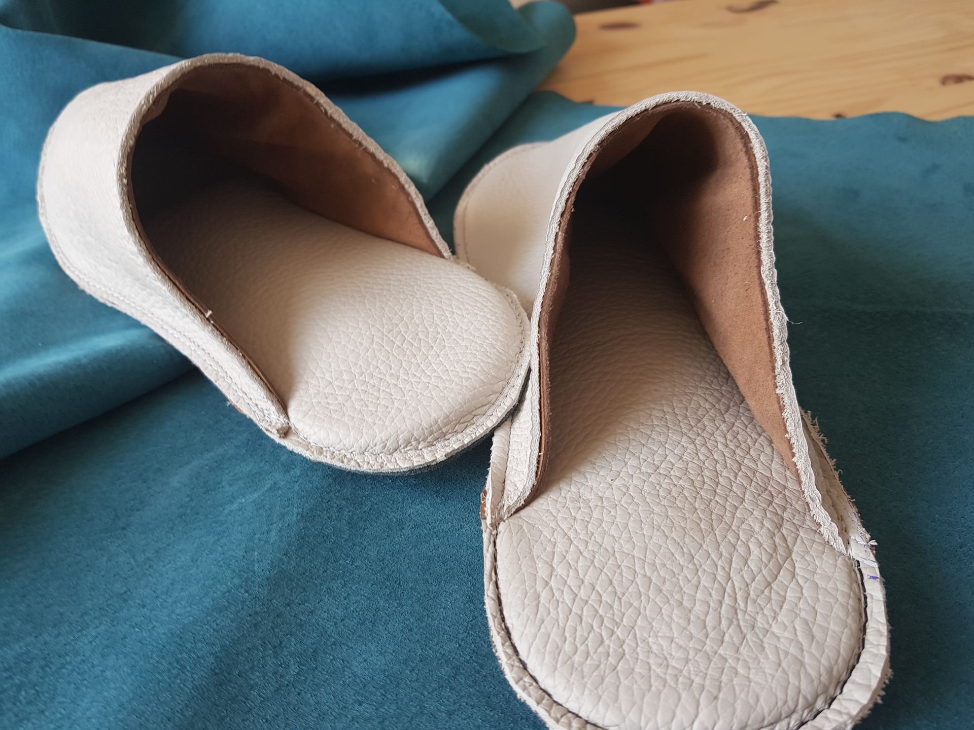 Une paire de pantoufles blanches est posée sur un tissu bleu