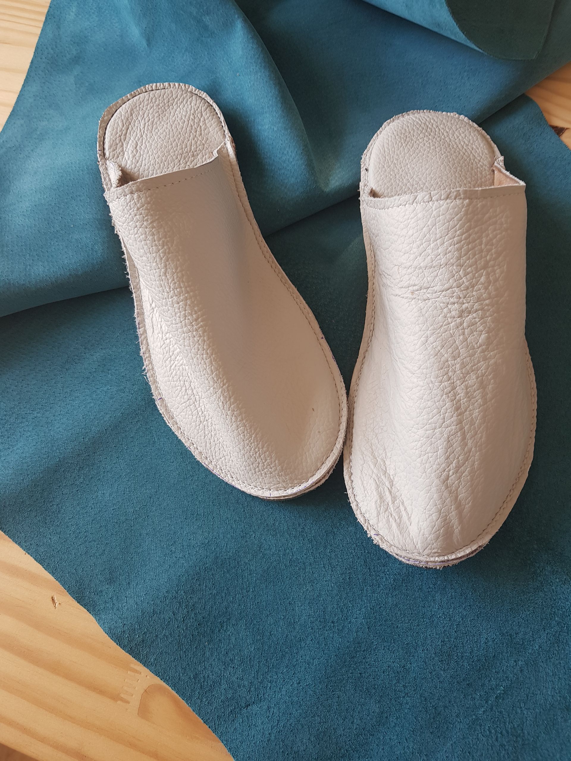 Une paire de pantoufles blanches est posée sur un tissu bleu.