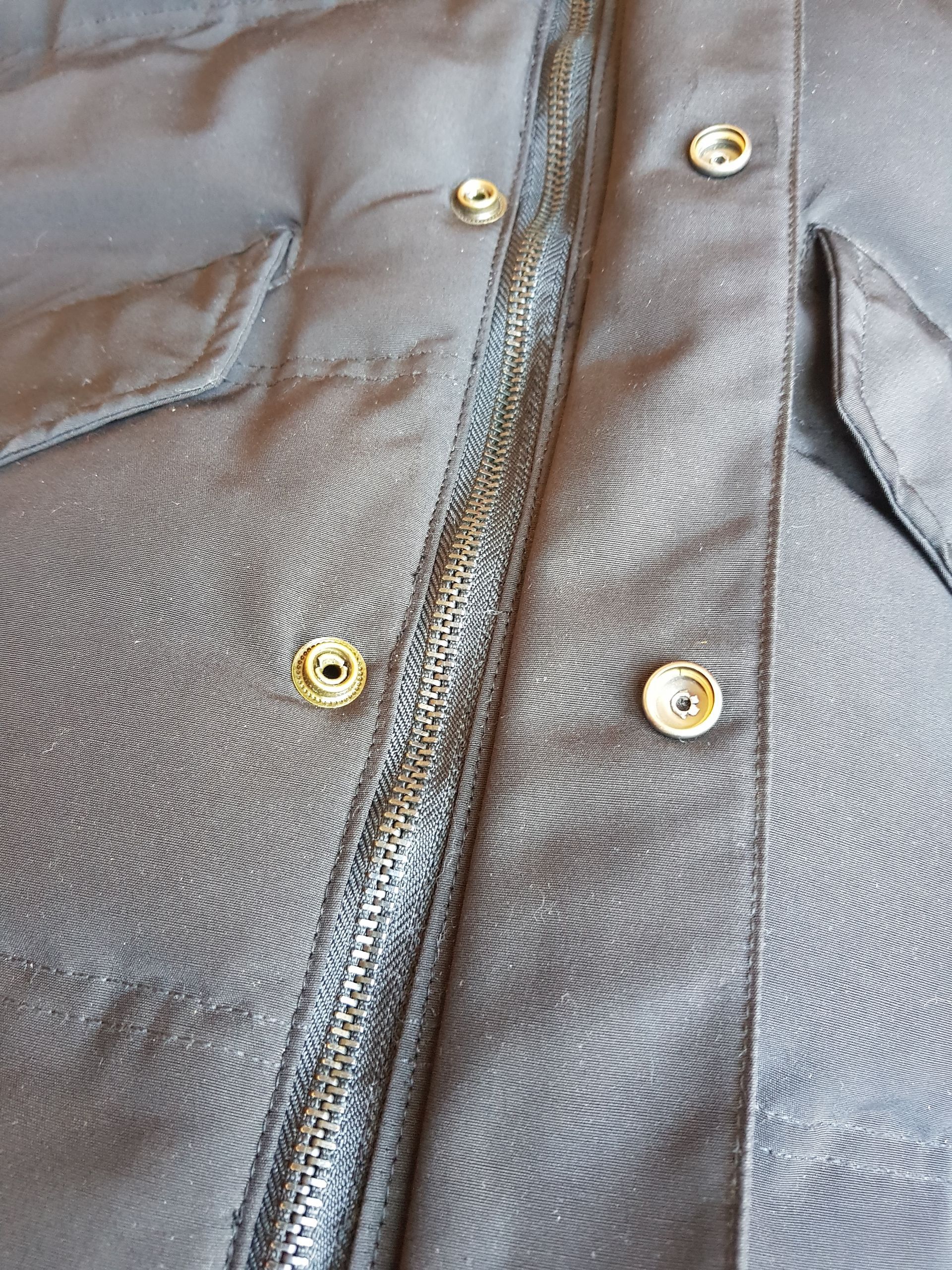 Un gros plan d'une veste noire avec des boutons et une fermeture éclair.