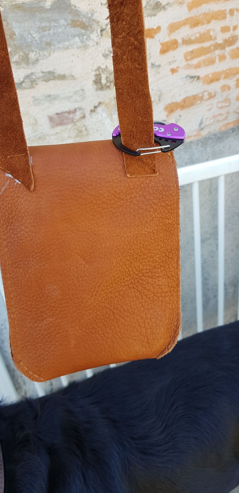 Un gros plan d'un sac en cuir marron avec un bouton violet dessus.