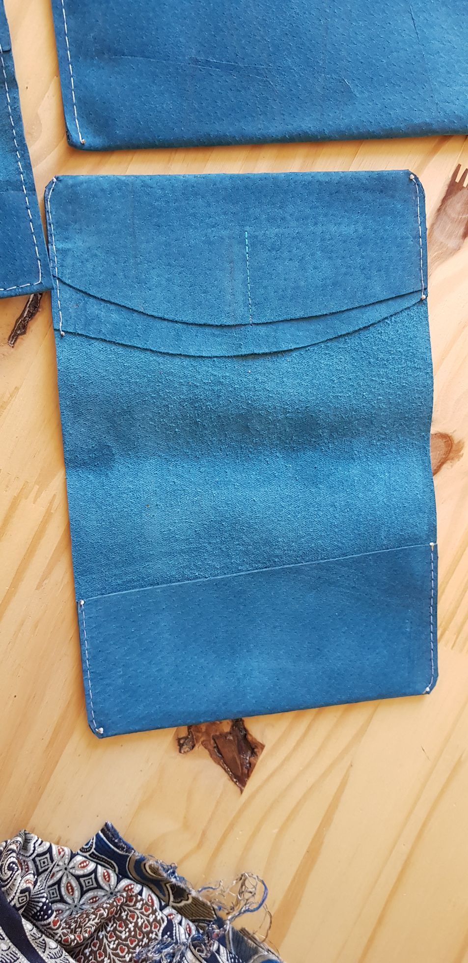 Un portefeuille bleu est posé sur une table en bois.