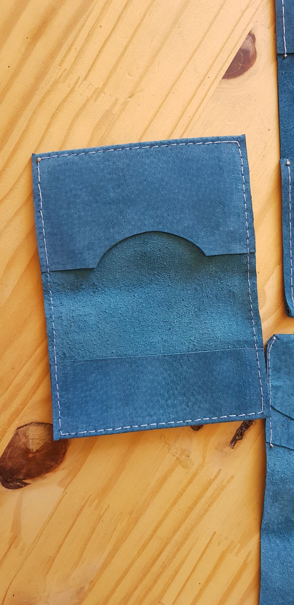 Un portefeuille en cuir bleu est posé sur une table en bois.