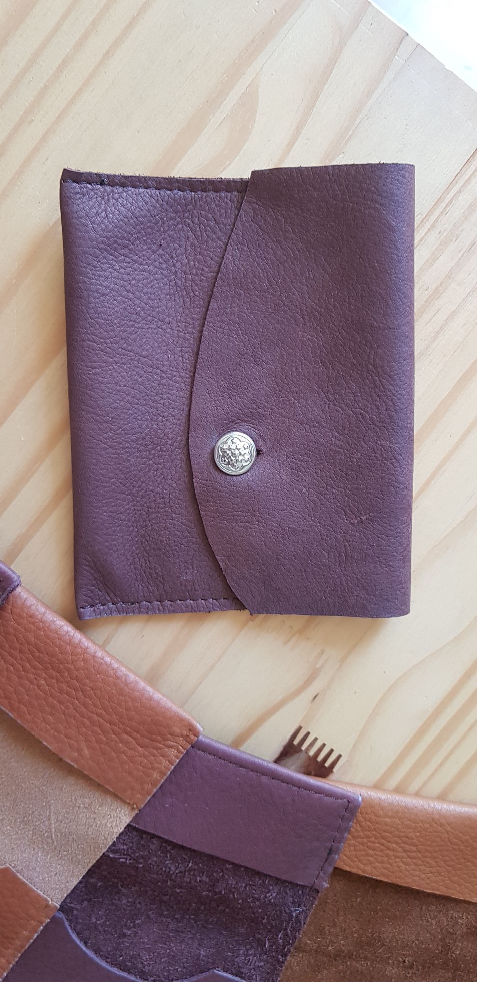 Un portefeuille en cuir violet est posé sur une table en bois.