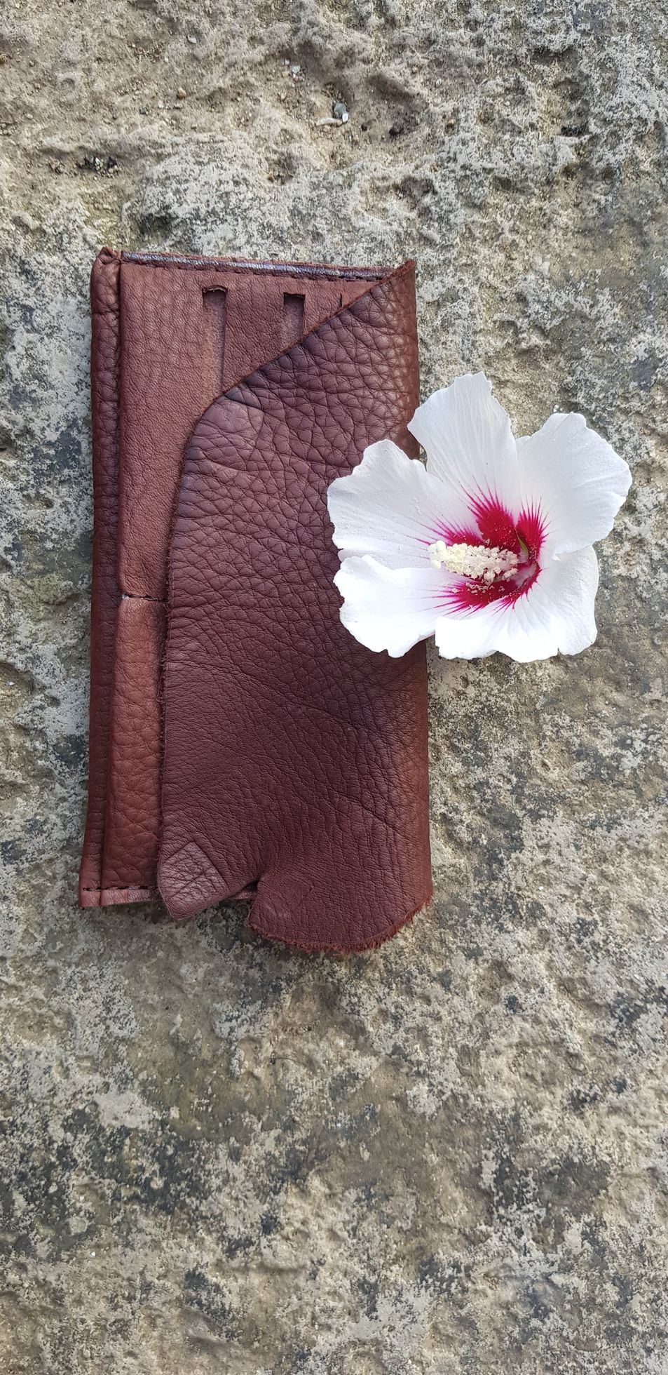 Une fleur blanche est posée sur un morceau de cuir marron.