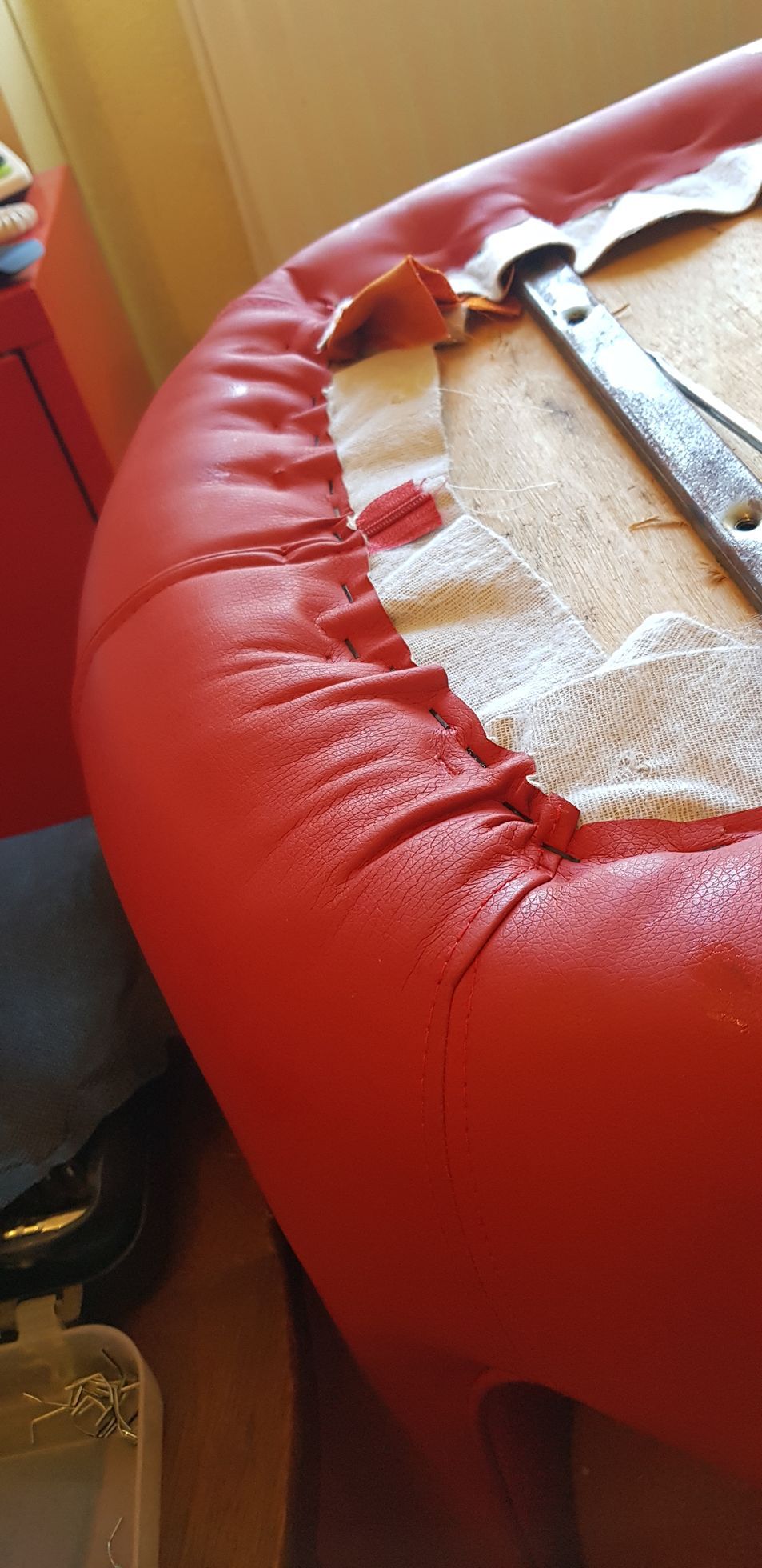 Une chaise en cuir rouge est posée sur un parquet à côté d'une fenêtre.
