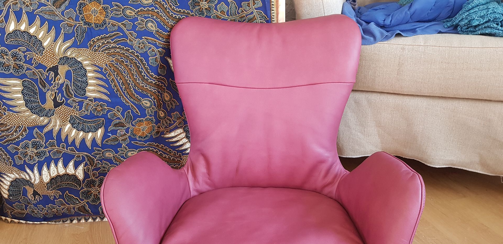 Une chaise rose est posée dans un salon à côté d’un canapé.