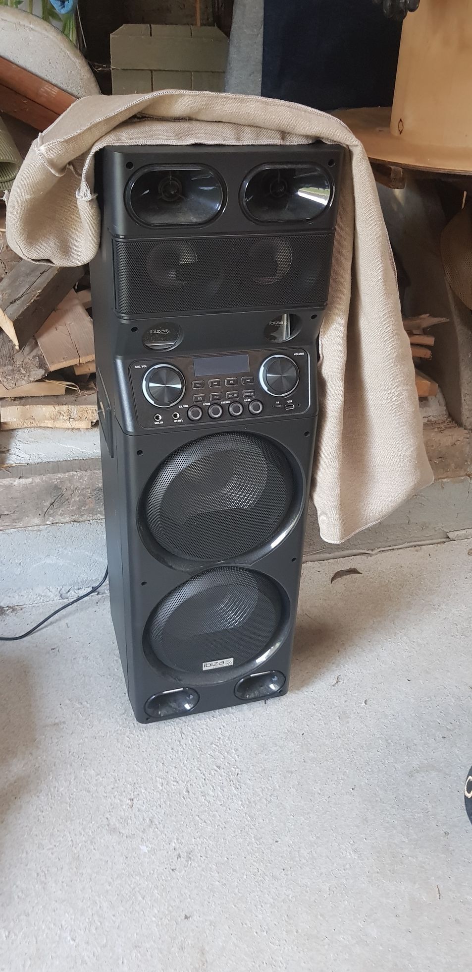 Un haut-parleur entouré d’une serviette est posé sur le sol.