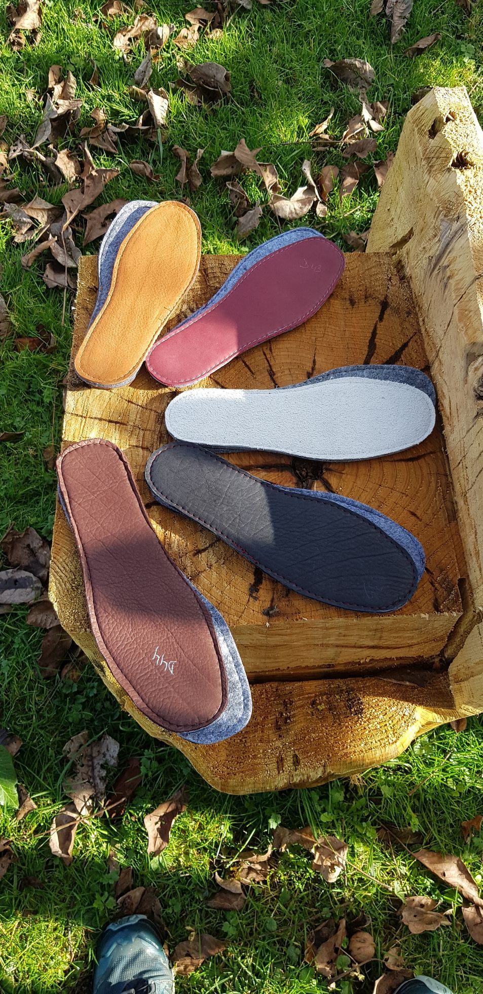 Un tas de semelles de chaussures de différentes couleurs sont posées sur un morceau de bois.