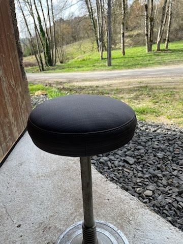 Un tabouret noir est posé sur un trottoir à côté d’une route.