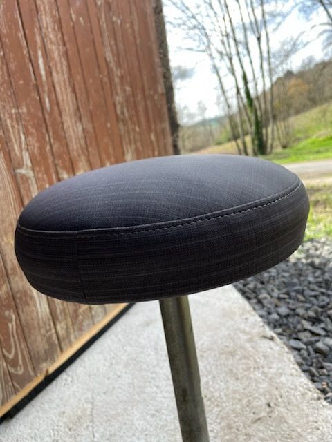 Un tabouret noir est posé sur un trottoir devant un bâtiment en bois.