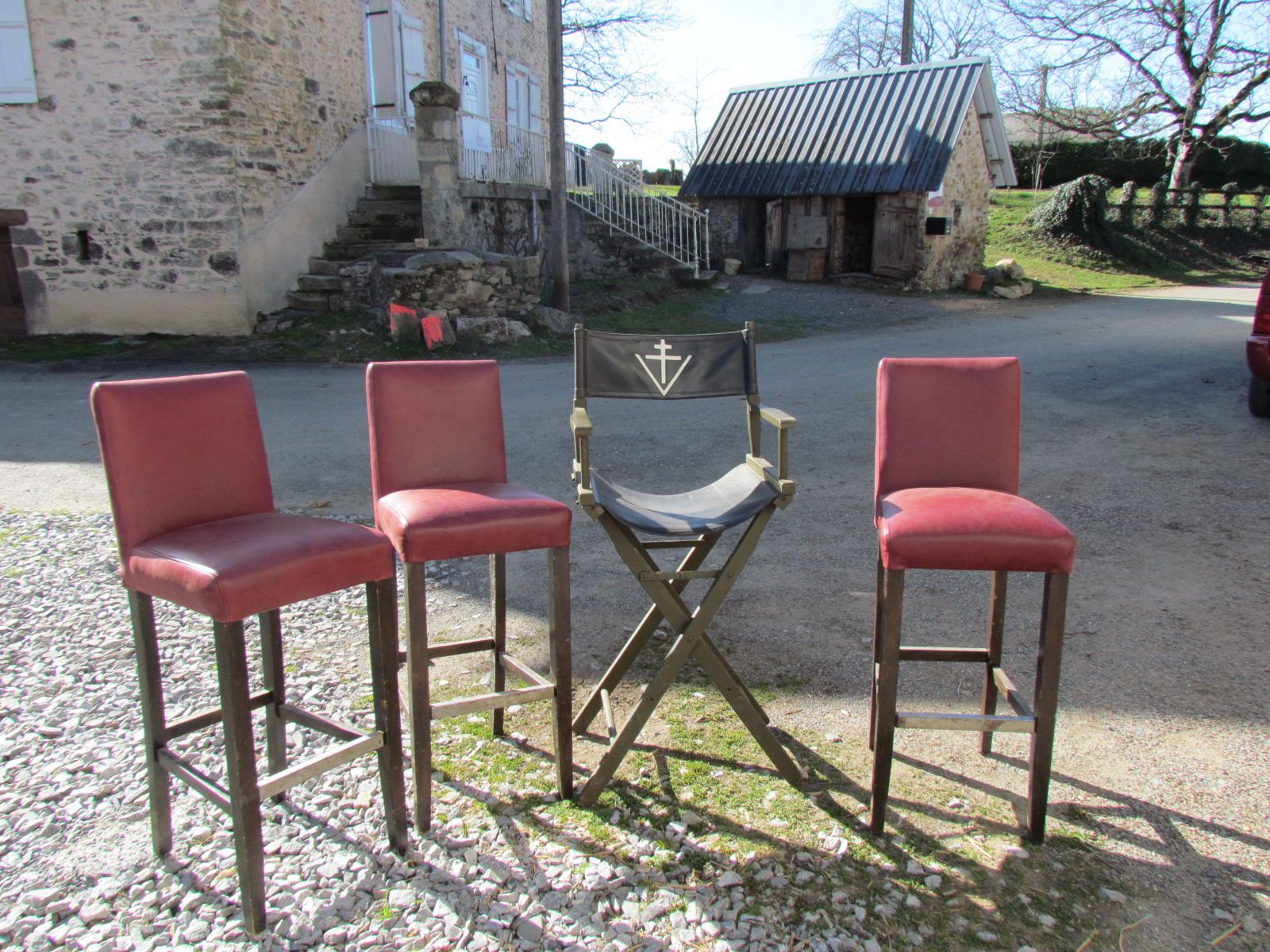 Trois tabourets de bar rouges et une chaise de réalisateur devant un immeuble