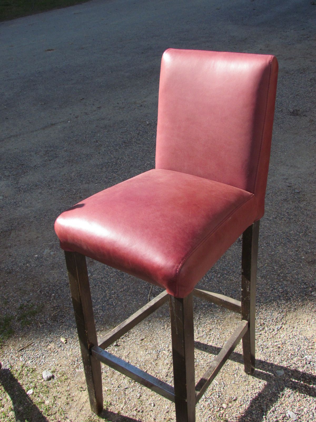 Un tabouret de bar en cuir rouge est posé sur le bord de la route