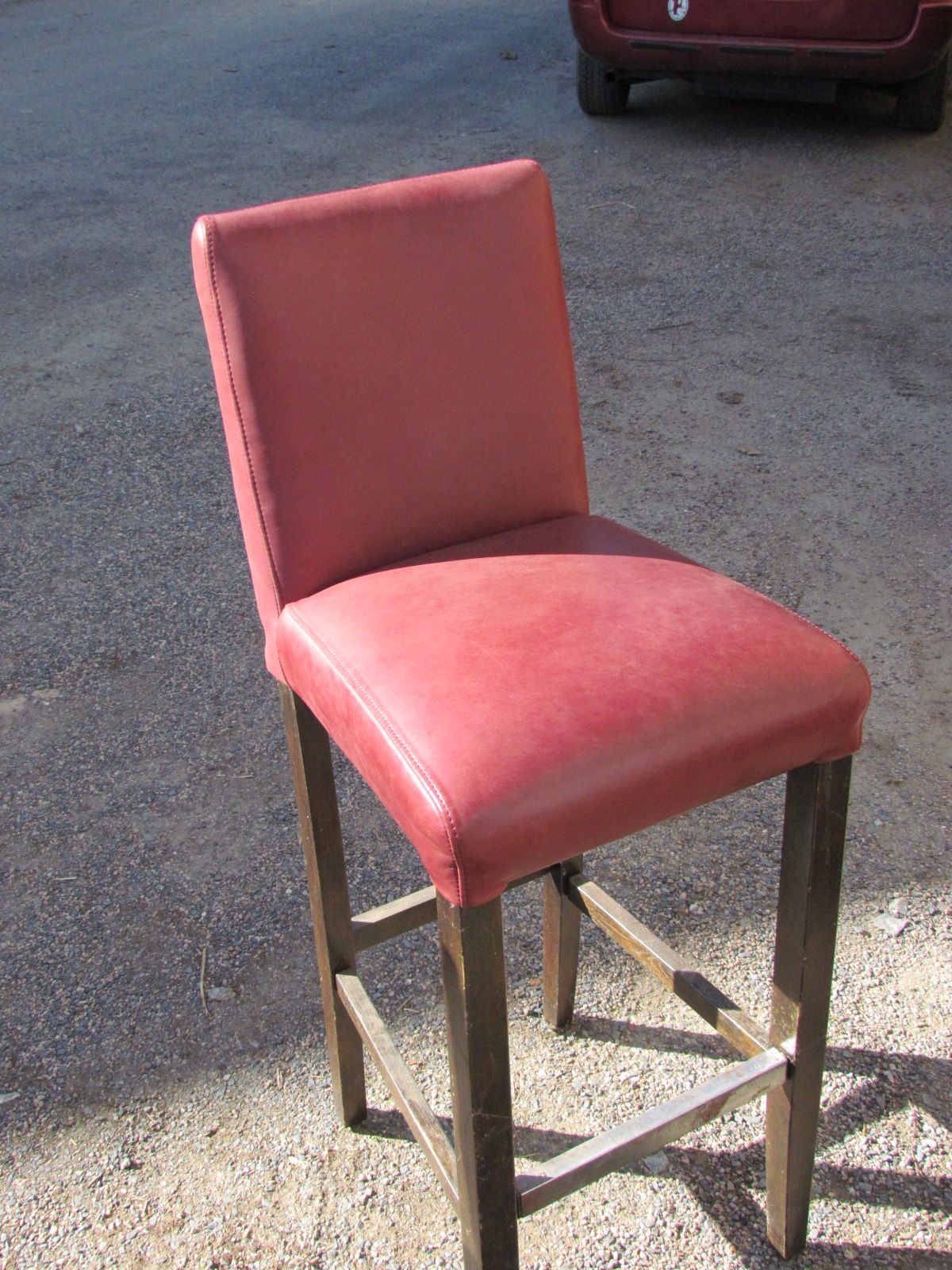 Une chaise en cuir rouge est posée sur le bord de la route