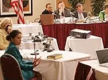 A group of people are sitting at tables in a conference room.