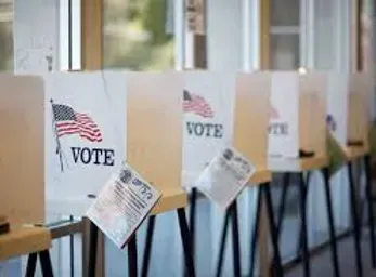 A row of voting booths are lined up in a room.